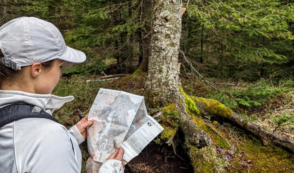 A woman reads a map on a trail.