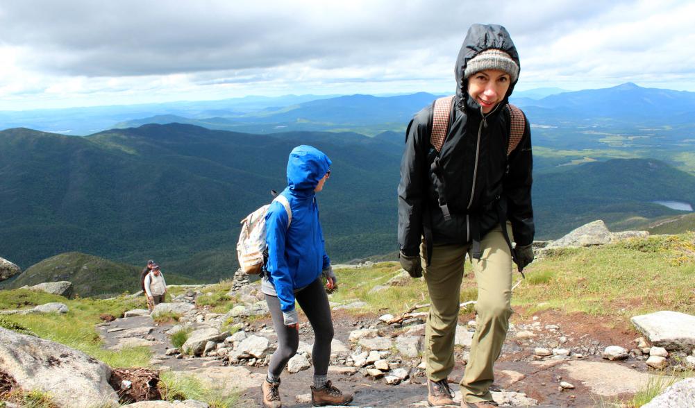 Four hikers climb a mountain with the high peaks in the background