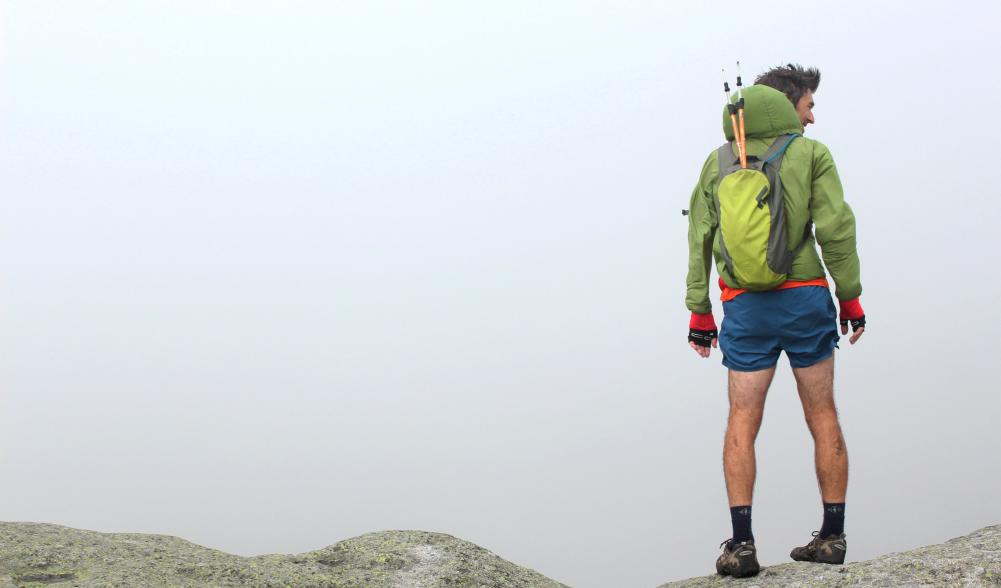 A man stands on top of a rocky point.