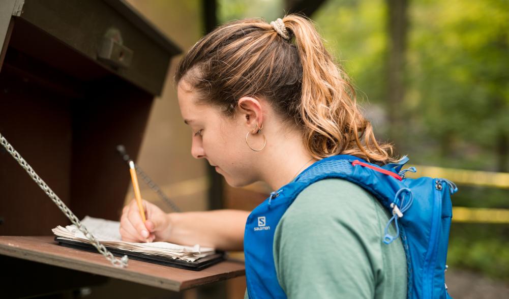 A woman signs in to a trail.