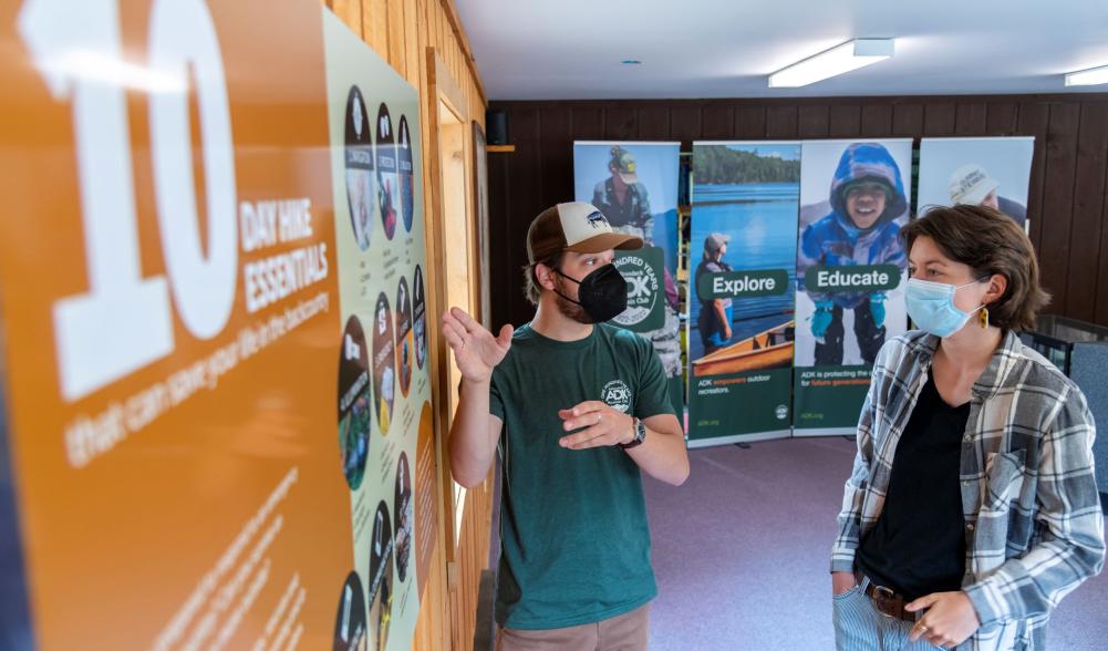 A guide helps a visitor read an information poster.