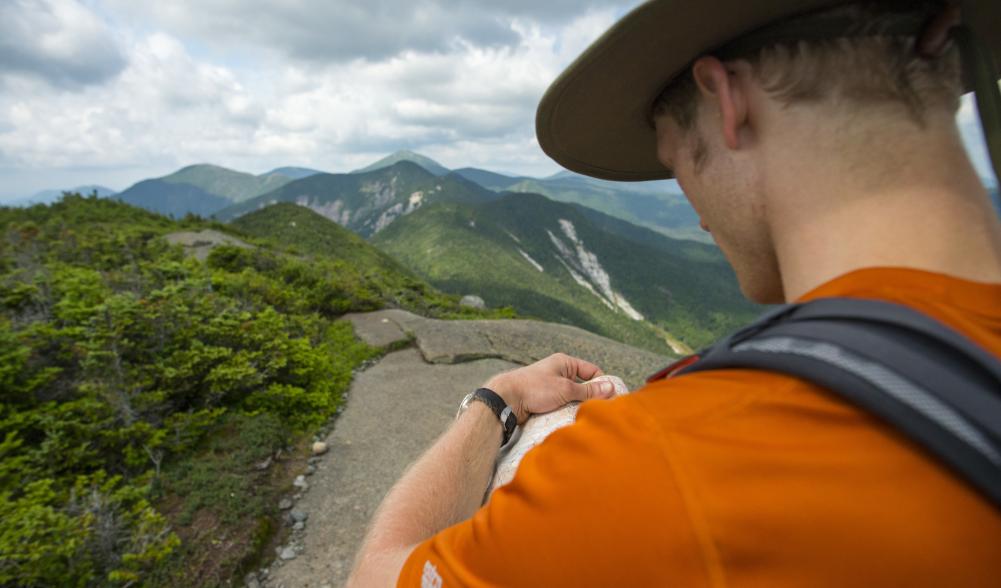 A hiker checks a map on the summit of a mountain