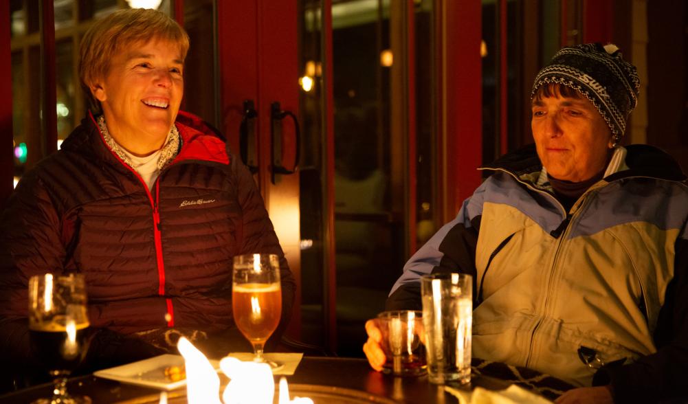 two women eating food by a campfire