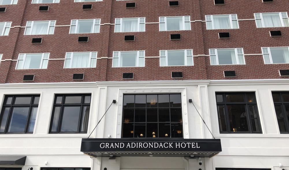 A street view of Grand Adirondack from the street with windows and front entrance sign.