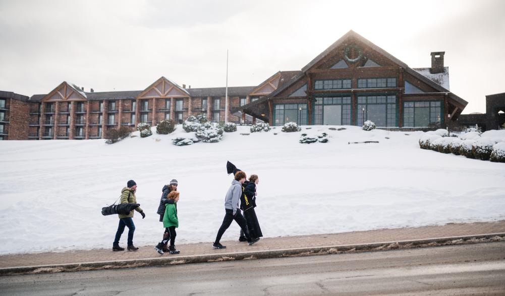 a family walks up a snowy sidewalk to the Crowne Plaza Hotel.
