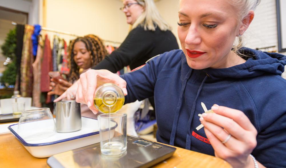 A woman pours oil into a glass jar in a shop.