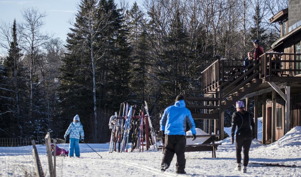 People outside the lodge at Cascade with skis on a rack