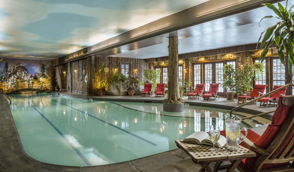 A view of the indoor pool at the Mirror Lake Inn Resort and Spa, with lounge chairs lining the edges of the pool walkway