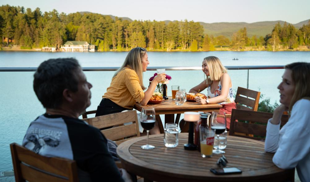 People dine outdoors on a deck overlooking Mirror Lake.