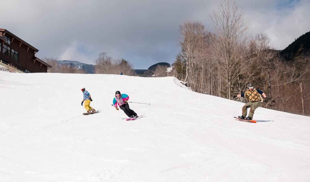 Skiers and boarders carve their way down a snowy slope.