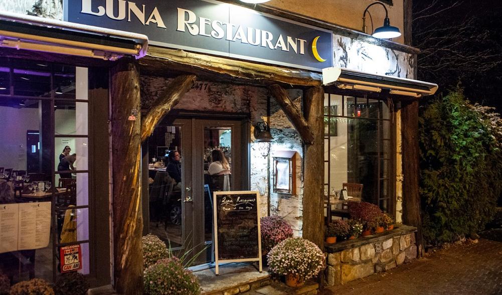 The exterior of a wood and birch bark trimmed restaurant. The sign reads Luna Restaurant.