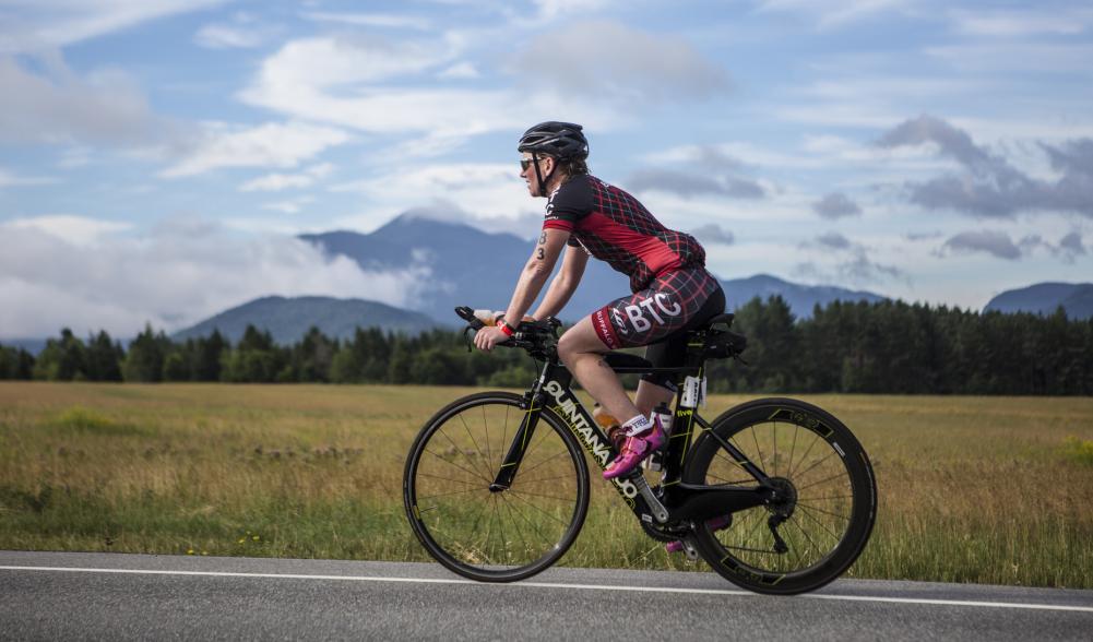 A cyclist rides the Ironman course amidst high peaks scenery in the Lake Placid Ironman competition