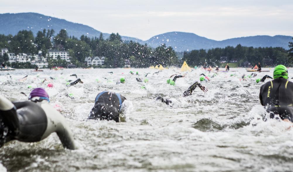 A group of swimmers splashes in the water of Mirror Lake on the morning of the Ironman Race in Lake Placid