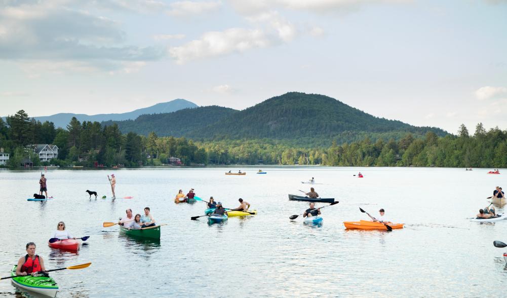 A group of kayaks floats in the water near the shore of Mid's Park in Lake Placid