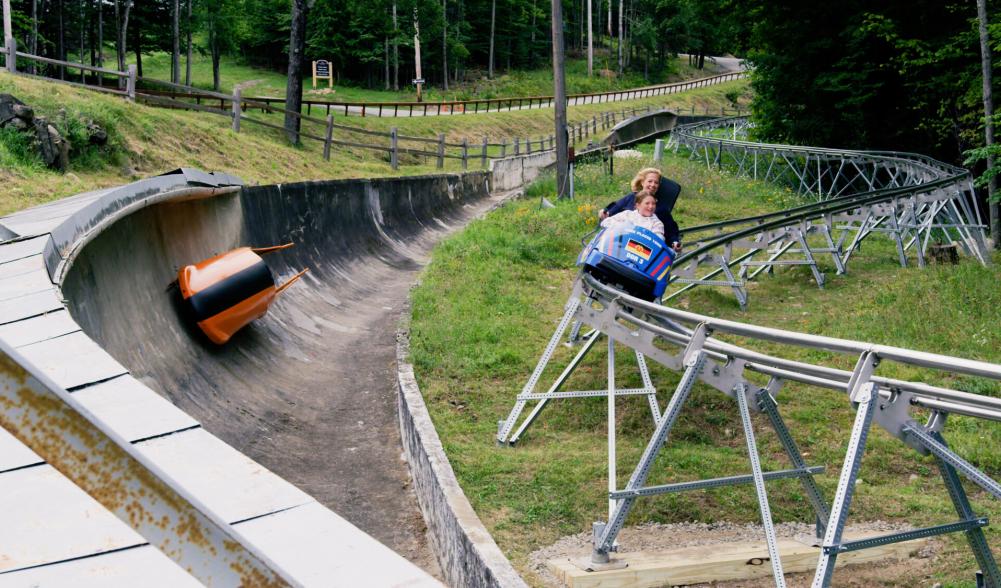 A woman rides a curve on a mountain coaster rail.