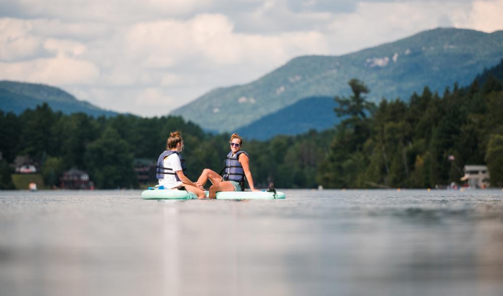 two women chat on SUPs in the middle of Mirror Lake.