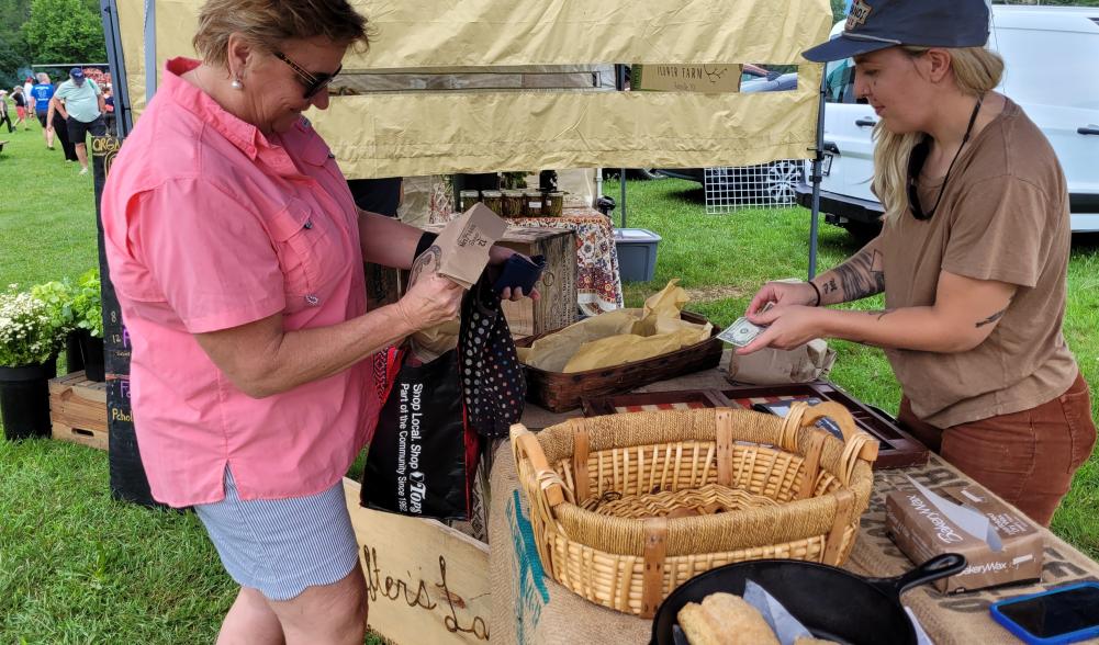 A woman buys a loaf of bread from Courtney Marvin at The Drifters Loaf, located at the Keene Farmers Market
