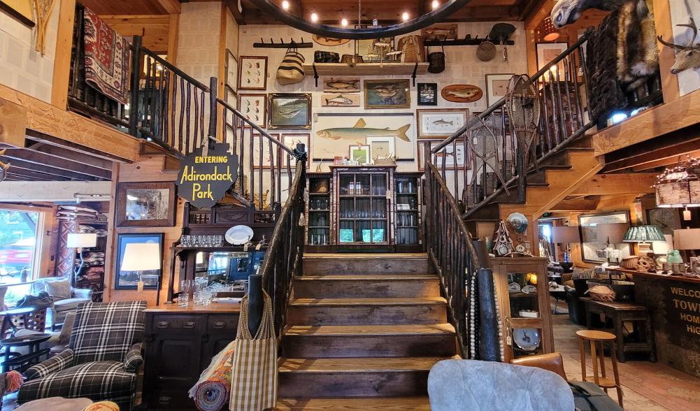 The interior of Dartbrook Rustic Goods is steeped in Adirondack style. A grand staircase leads to the second floor with home decor items throughout the building.