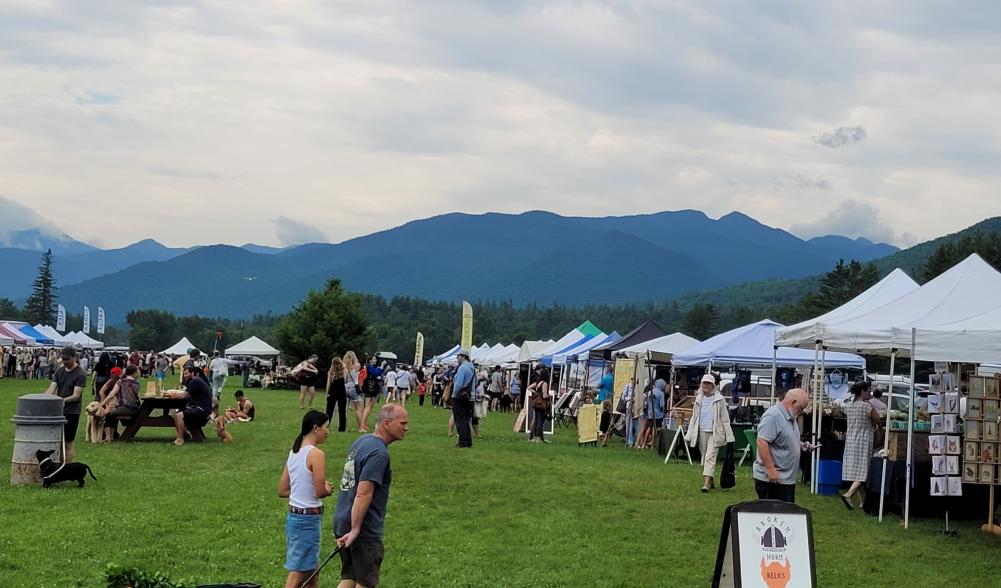 The Keene farmers market hosts many vendors, hundreds of people with their dogs, and offers a scenic view at the side of March field. The Adirondack Mountains are in the background.