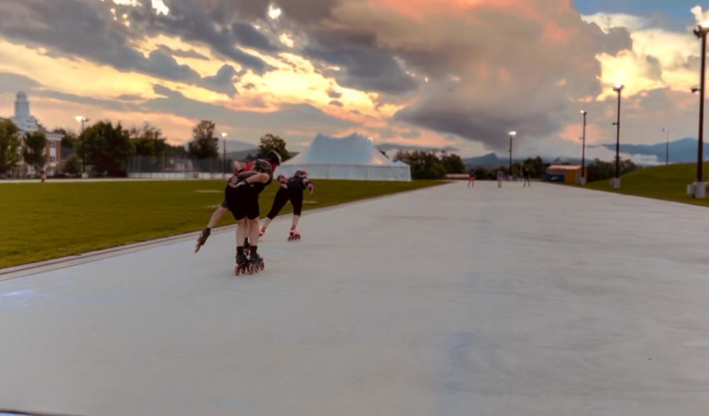 Two inline skaters race towards a pink sunset.
