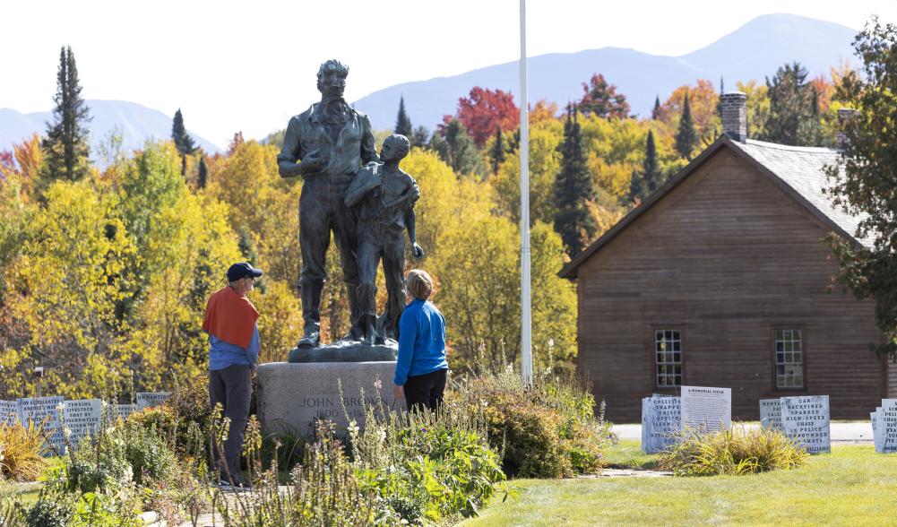 Two people view a memorial statue at John Brown Farm in Lake Placid