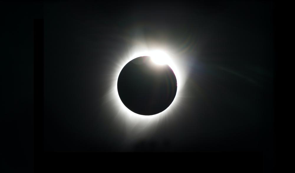 A black sky shows a total solar eclipse: a ring of white light surrounding a black disk, which is the moon