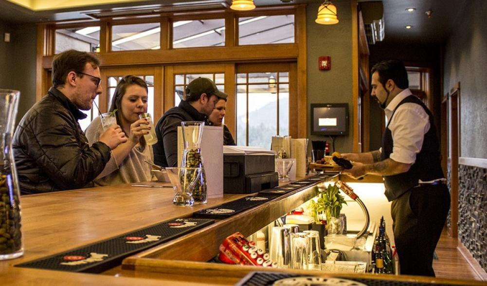 A bar tender serves patrons at a lodge-themed bar.