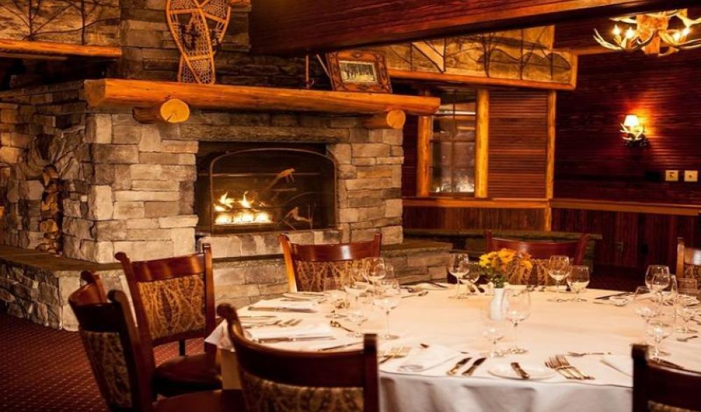 A lodge-style dining room with a large stone fireplace.