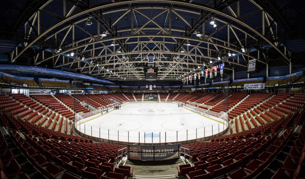 A panoramic view of a skating rink arena with red seats.