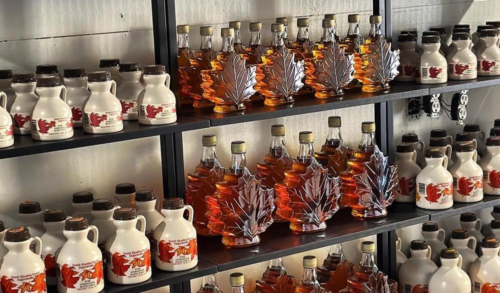 Store shelves stocked with plastic and glass containers of maple syrup