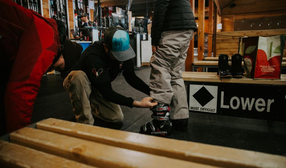A ski tech helps someone fit a boot.