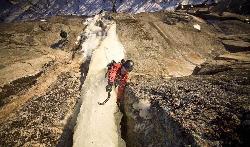 A person ice climbing a narrow dagger of ice