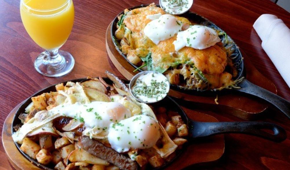 Two breakfast skillets served with orange juice.