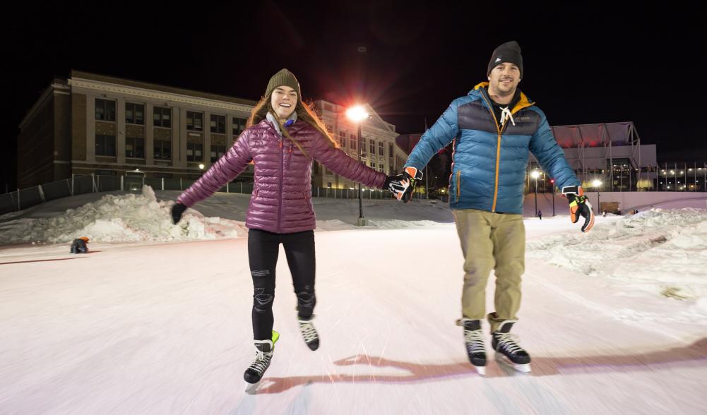 Two people skate during the evening hours after dark at the Olympic Oval