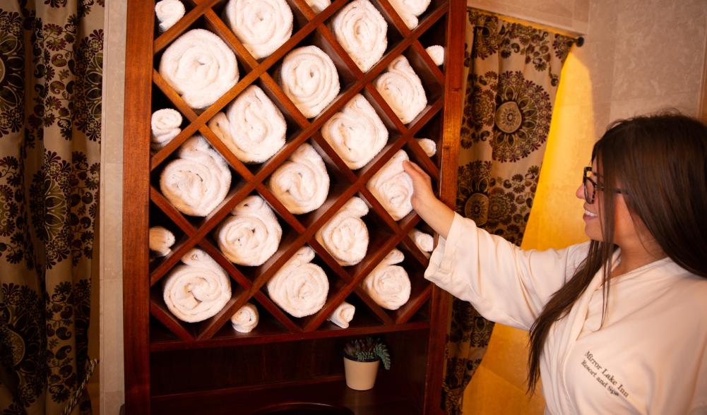 A woman selects a towel from a display in the spa at the Mirror Lake Inn