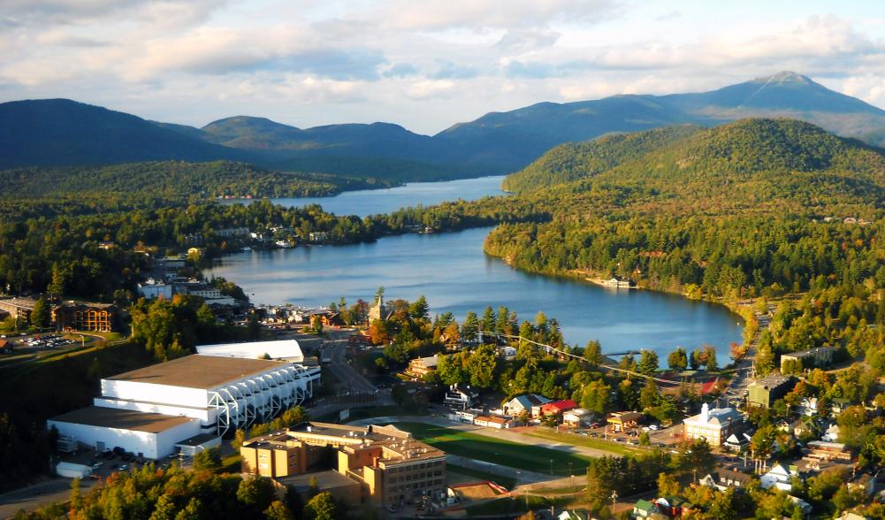 An aerial view of a town on a lake with wilderness around it.