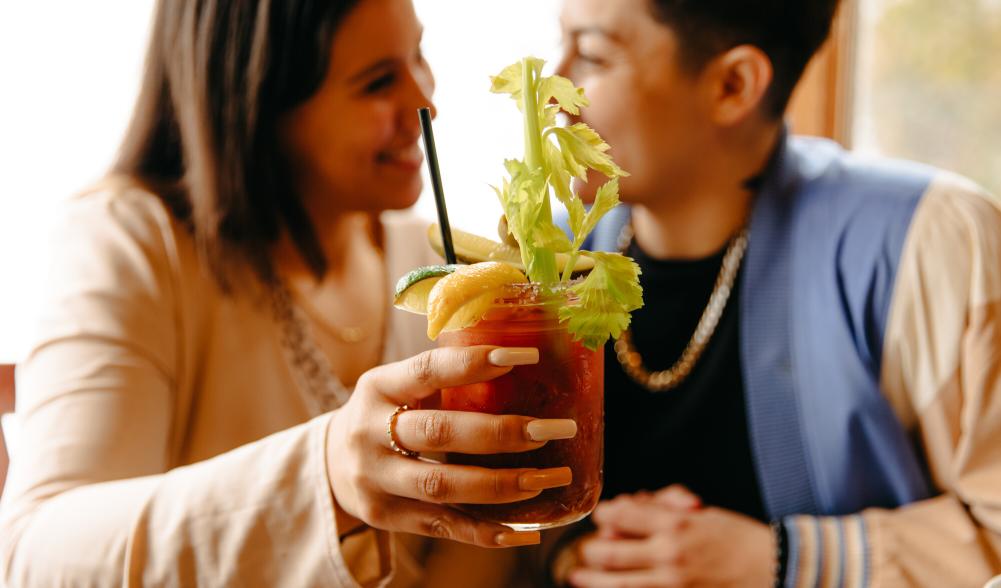 Couple holding up bloody mary in a jar