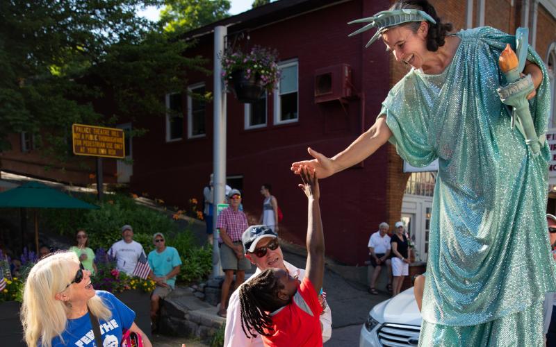 Girl reaches up the give a high five to a women dressed as the Statue of Liberty in the Lake Placid July 4th Parade