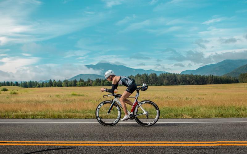 ironman biking on flat road past mountain view