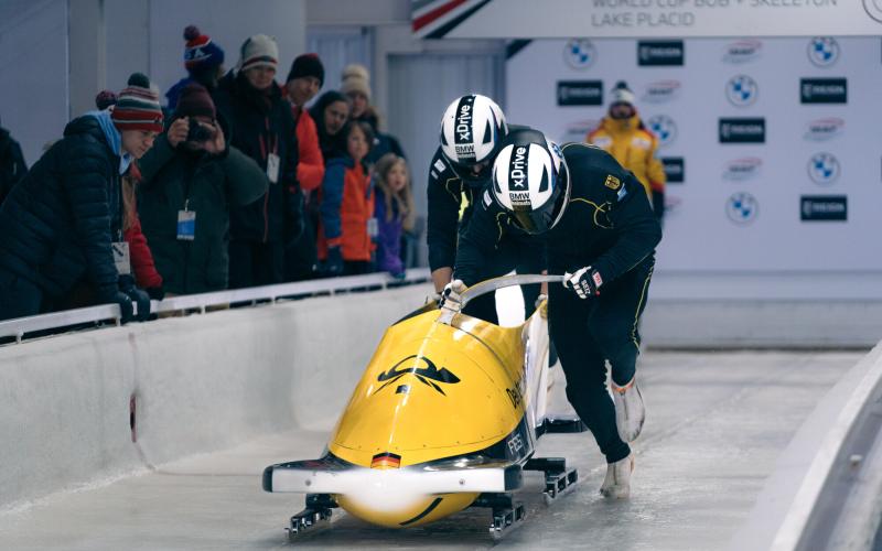 Two bobsled athletes pushing at a bobsled start.