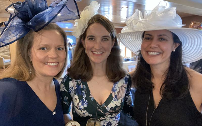Lovely ladies smile into the camera showcasing their fabulous derby hats