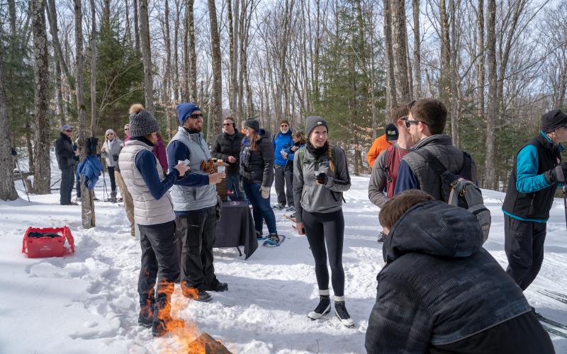 Cross-country skiers enjoying brews by a fire.