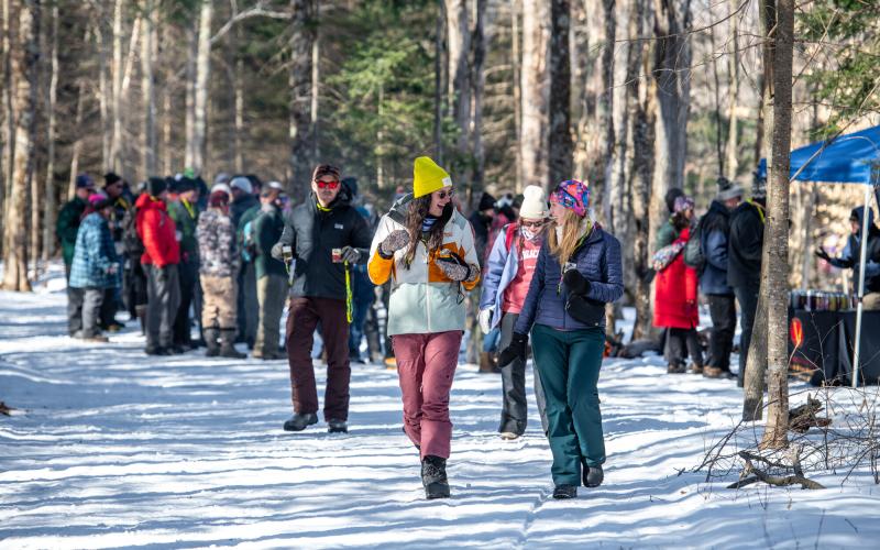 Two ladies walk down the trail with more brewski attendees behind them.