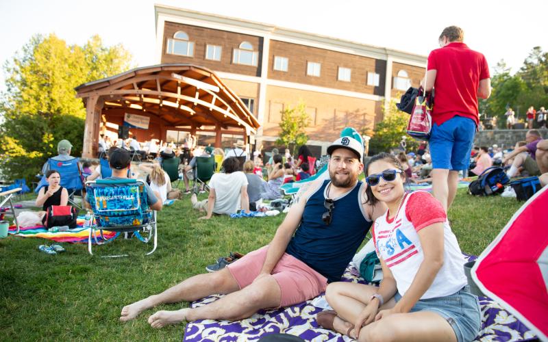 A couple lounges on a blanket in Mid's Park wearing red white and blue