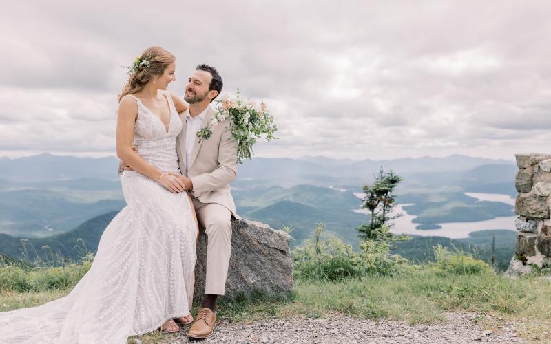 Bride and groom face each other in a grassy field with mountain views