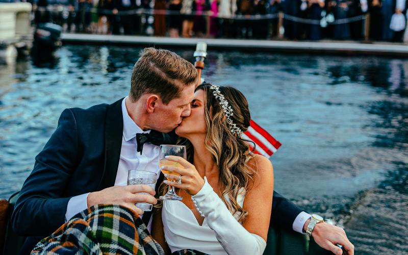 A bride and groom ride into the sunset on a Chris Craft wooded boat