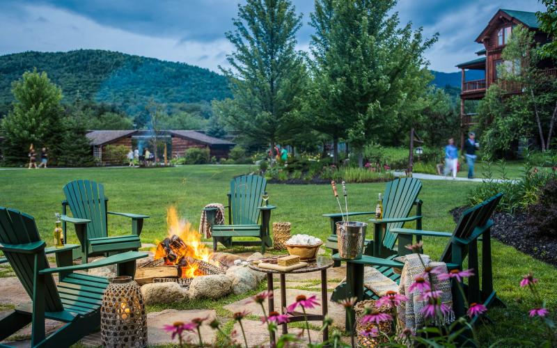 Adirondack chairs around an outdoor fire place.