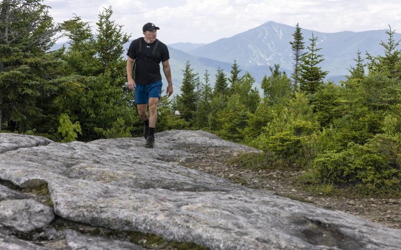 A hiker walks on a rocky summit