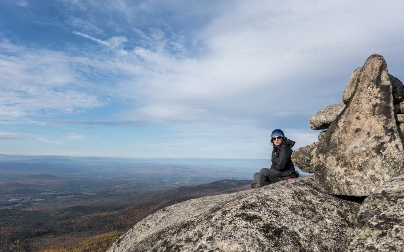 A hiker sits on the rocks on a summit