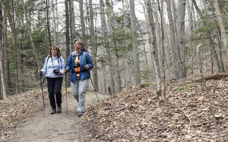 Two woman hike a flat trail in the woods